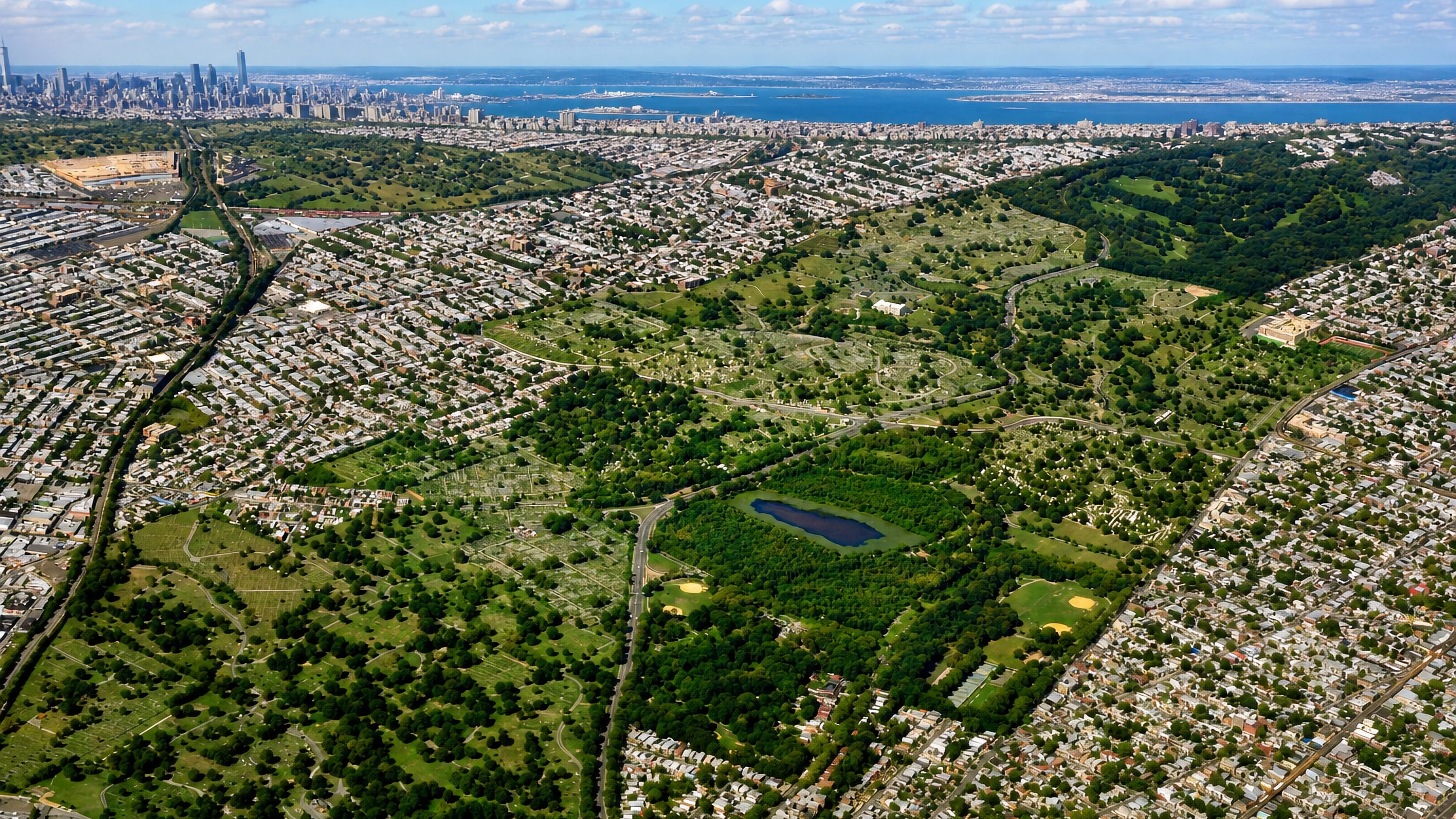Aerial view of Cypress Hills, New York City, its cemeteries and parkland with the Manhattan skyline beyond.