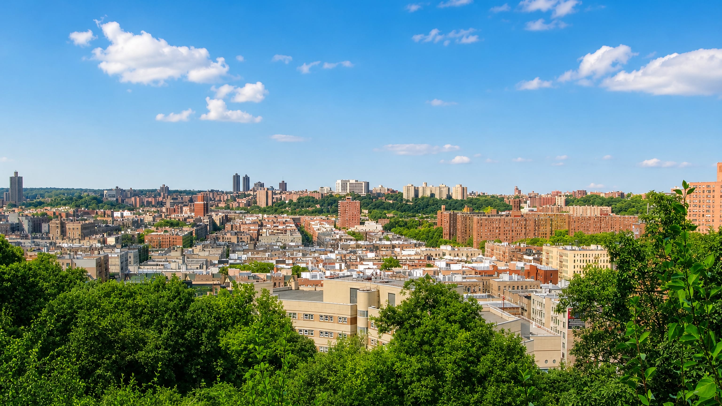Northern Manhattan rooftops and apartment blocks seen across treetops from the heights of Inwood, New York.
