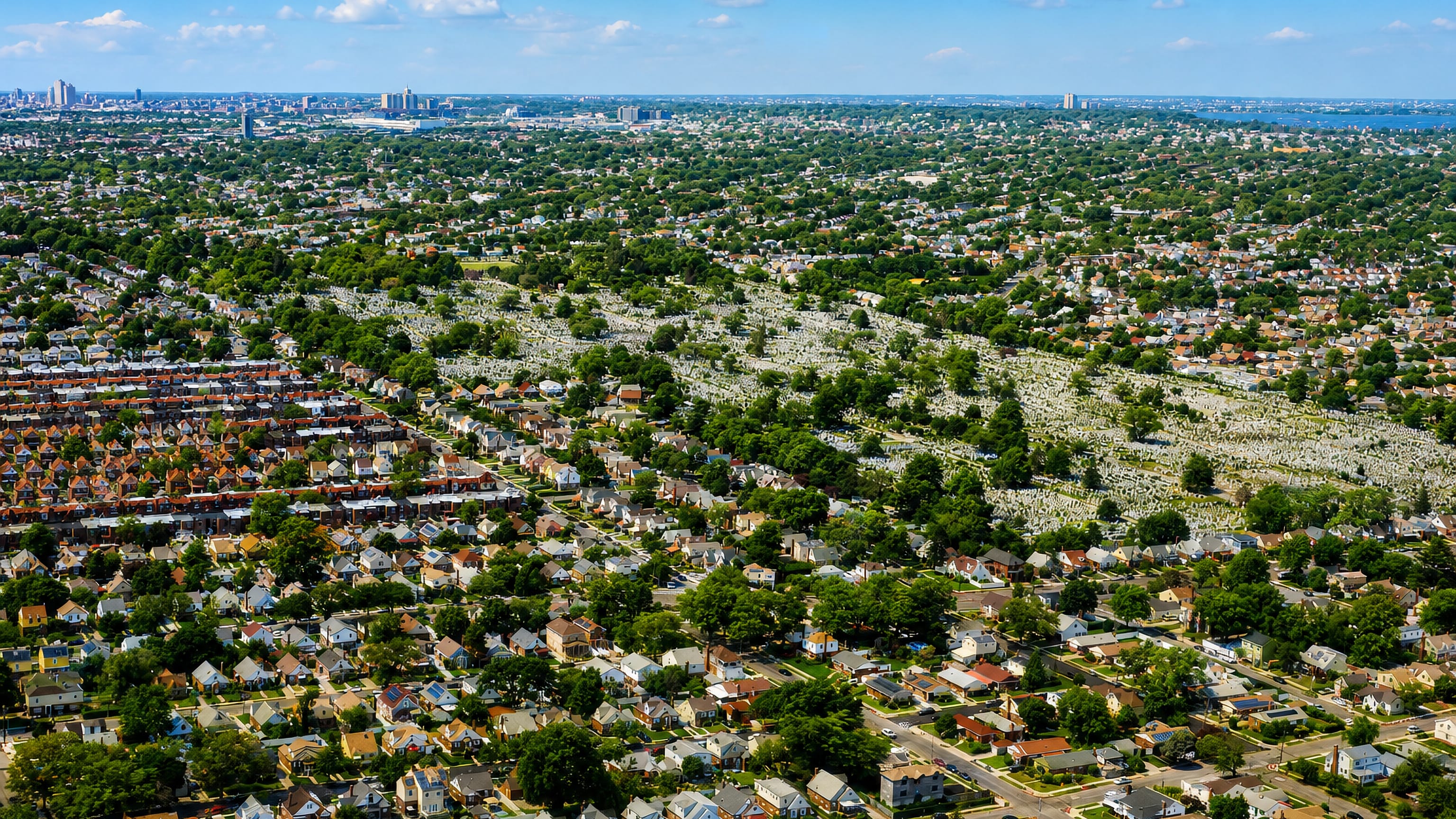 Aerial view over Laurelton, Queens, with detached houses, tree-lined streets and a large cemetery beyond.