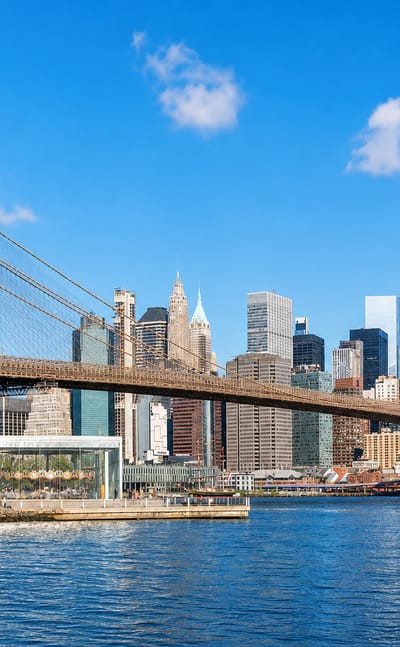 The Brooklyn Bridge spanning the East River with the Lower Manhattan skyline and One World Trade Center behind it.
