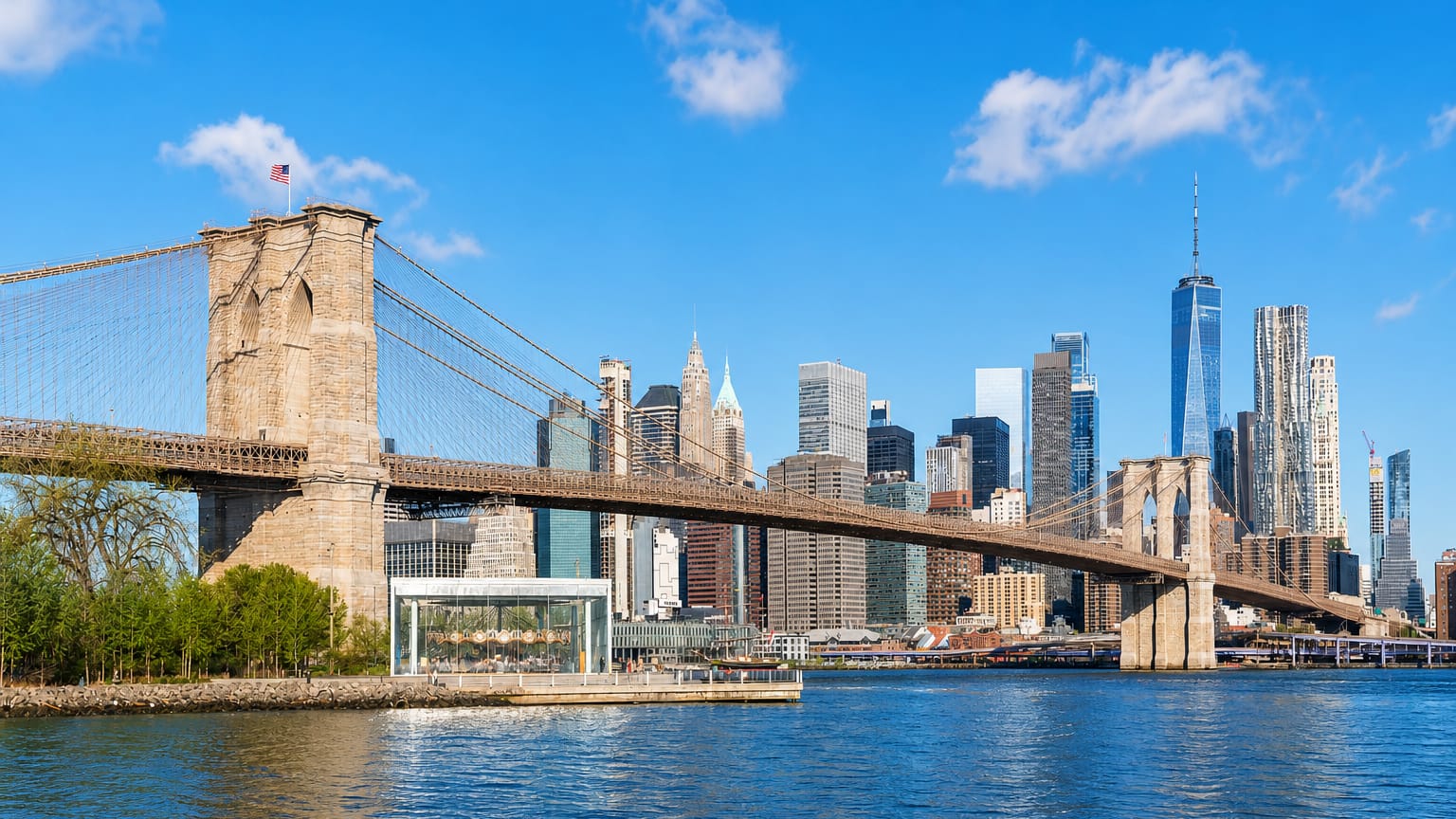 The Brooklyn Bridge spanning the East River with the Lower Manhattan skyline and One World Trade Center behind it.