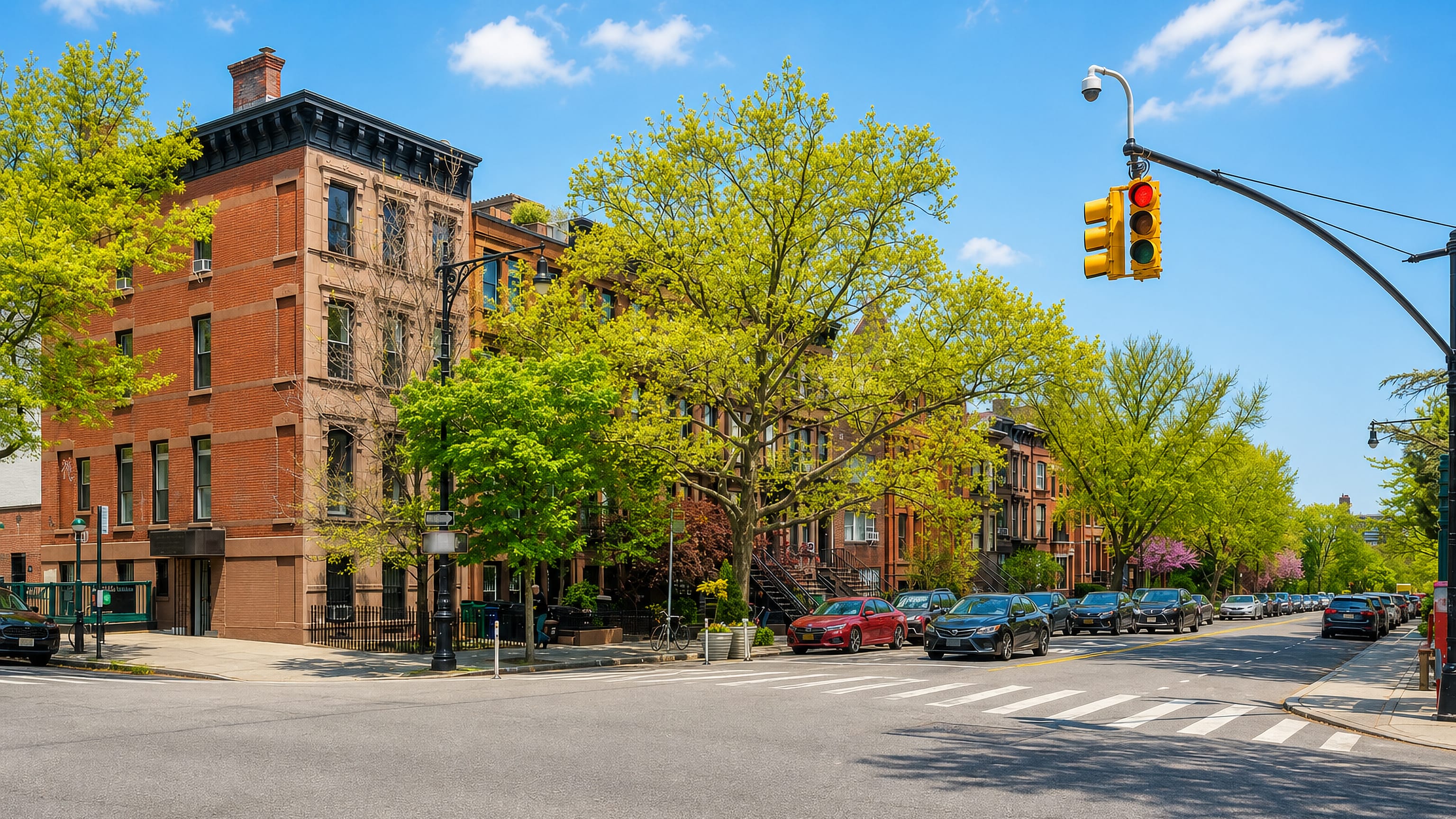 Brownstone row houses and spring trees along a quiet corner in Park Slope, Brooklyn, New York City.