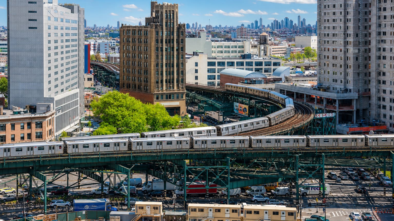 Aerial view over the low-rise residential sprawl of Queens, New York, toward a distant shore.