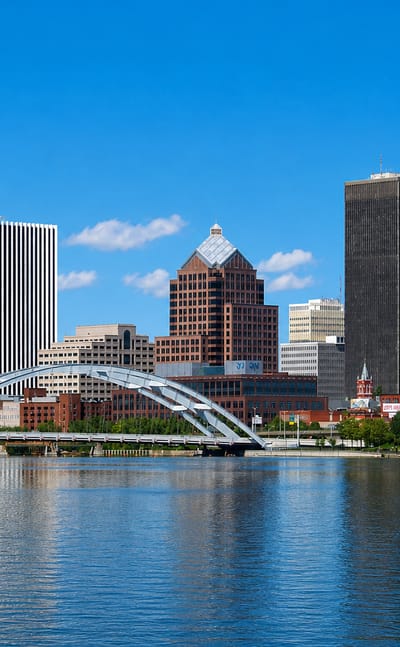 Rochester, New York skyline along the Genesee River with its arched pedestrian bridge and downtown towers.