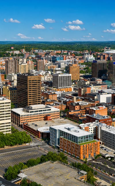 Aerial view of downtown Syracuse, New York with its domed stadium among mid-rise towers.