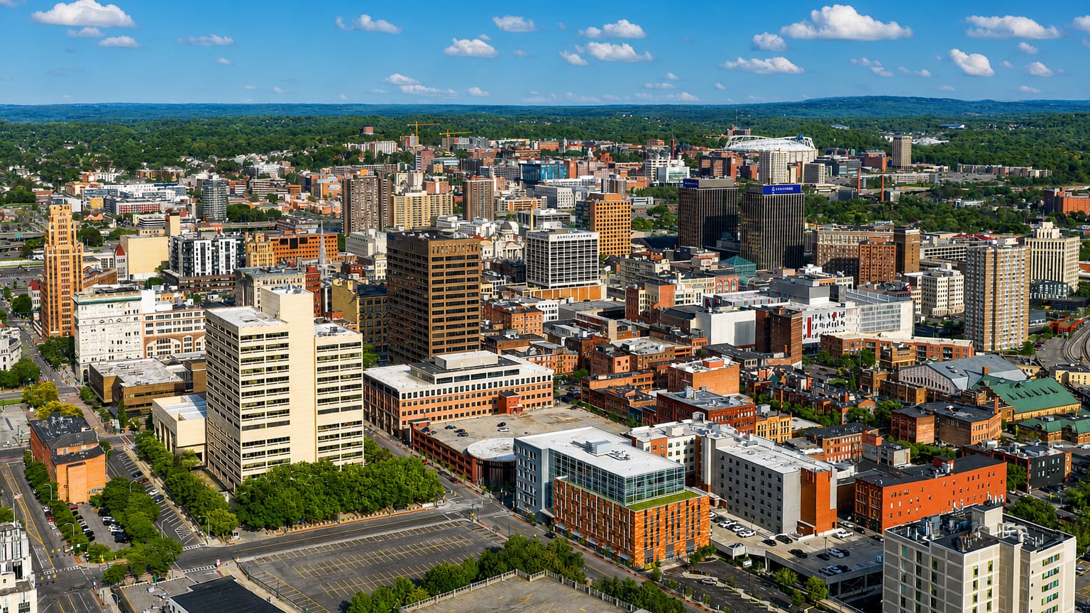 Aerial view of downtown Syracuse, New York with its domed stadium among mid-rise towers.