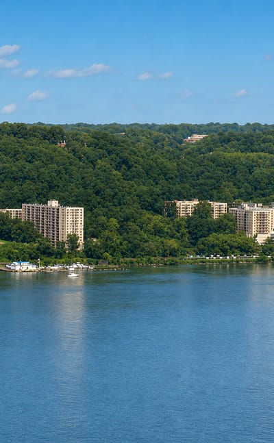 Wooded Hudson River bank with apartment towers and a hilltop water tower at Yonkers, New York.
