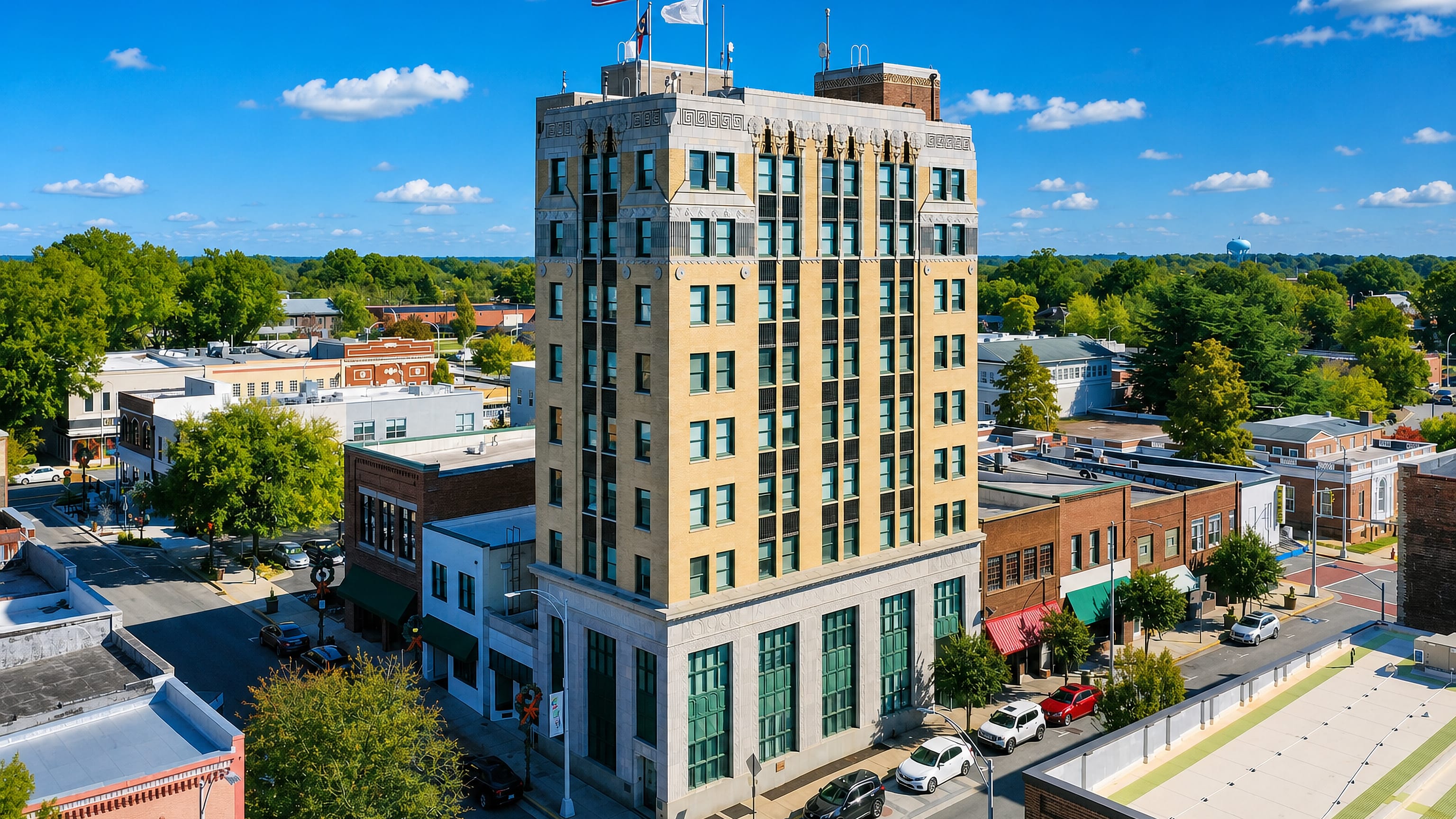 An art deco tower flying the US and North Carolina flags rises over downtown Burlington's brick storefronts.