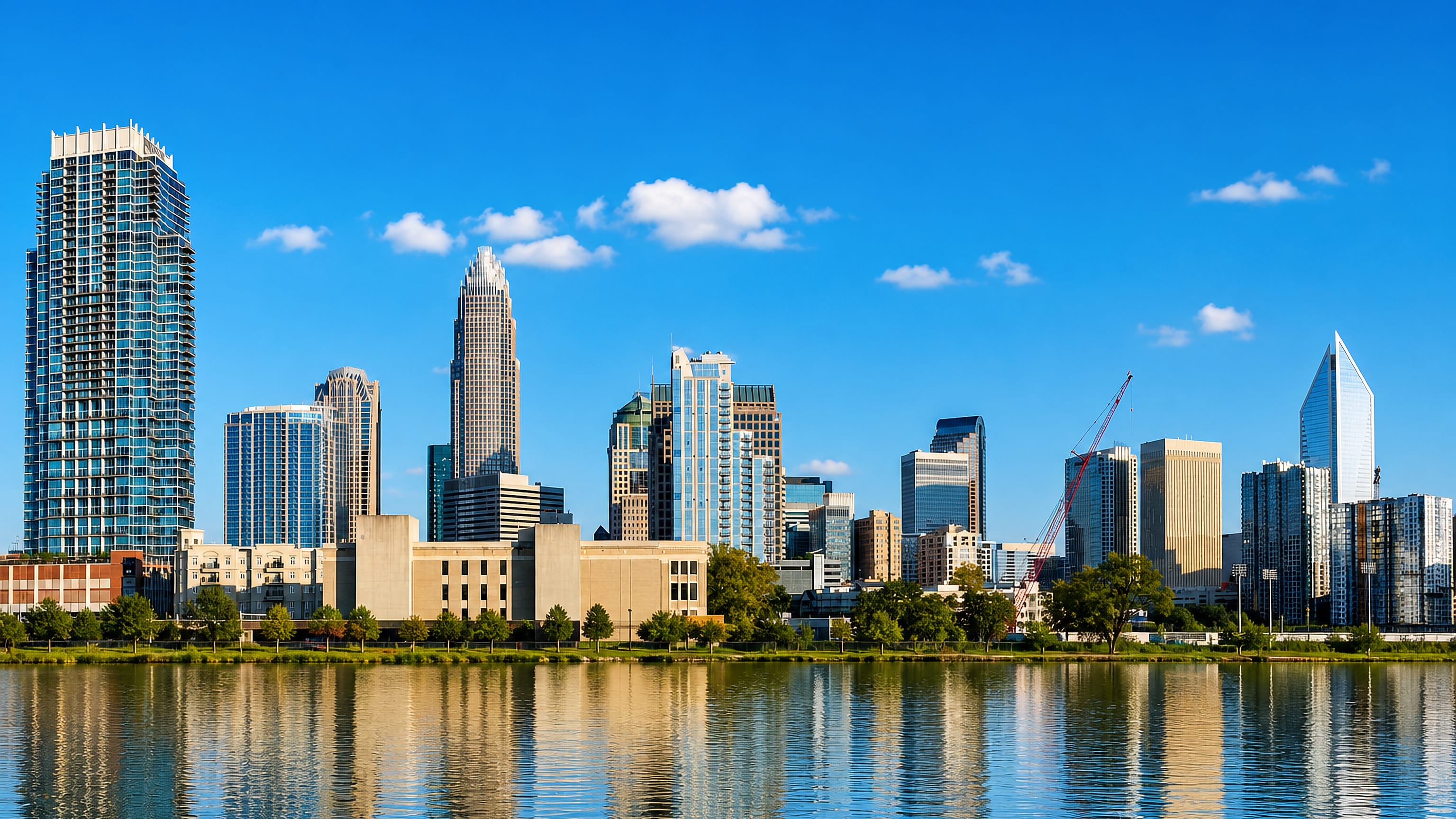 Uptown Charlotte skyline led by the Bank of America crown reflected in still water.