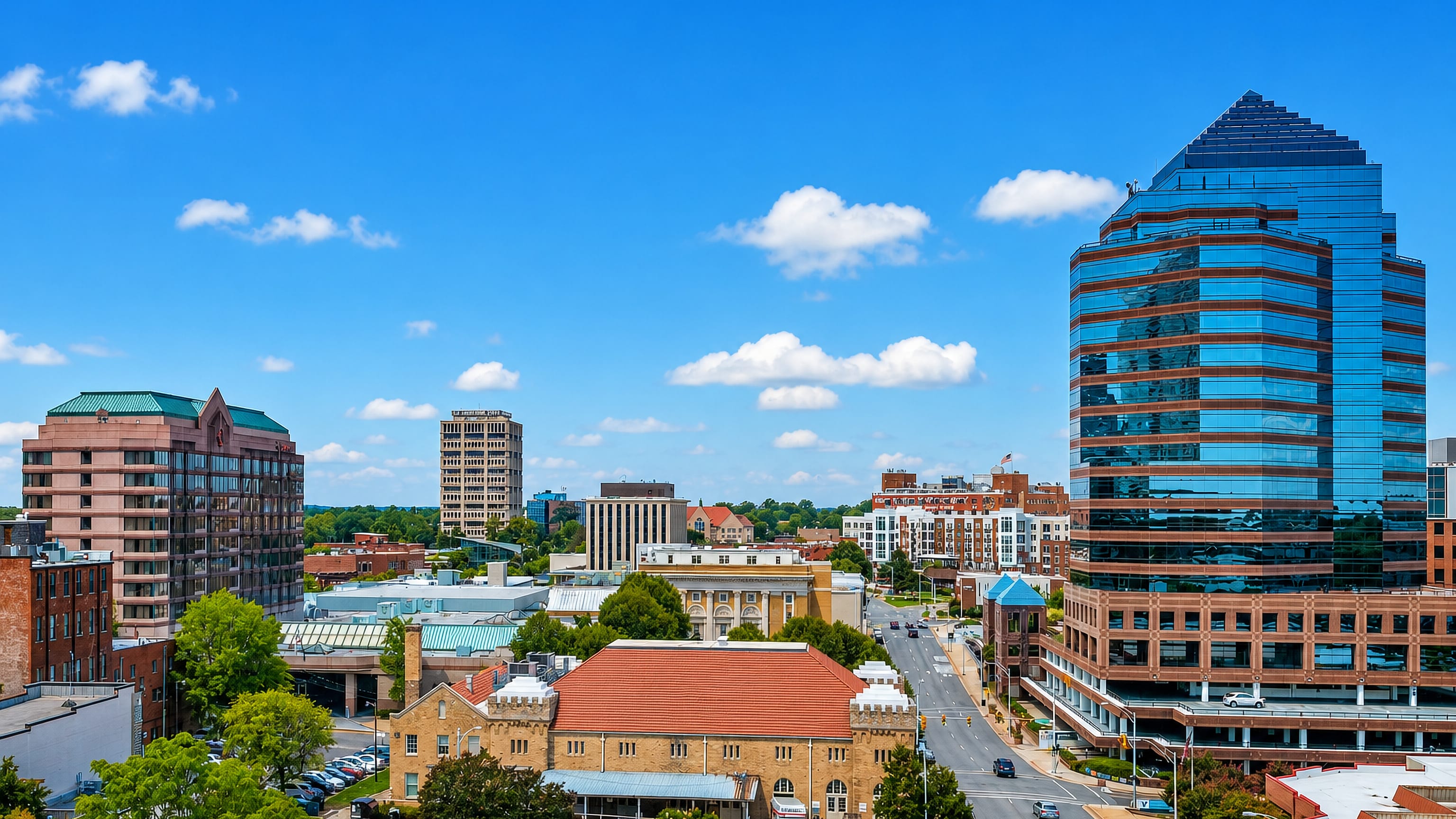 Downtown Durham, North Carolina, with a blue-glass office tower rising over brick blocks and a wide avenue.