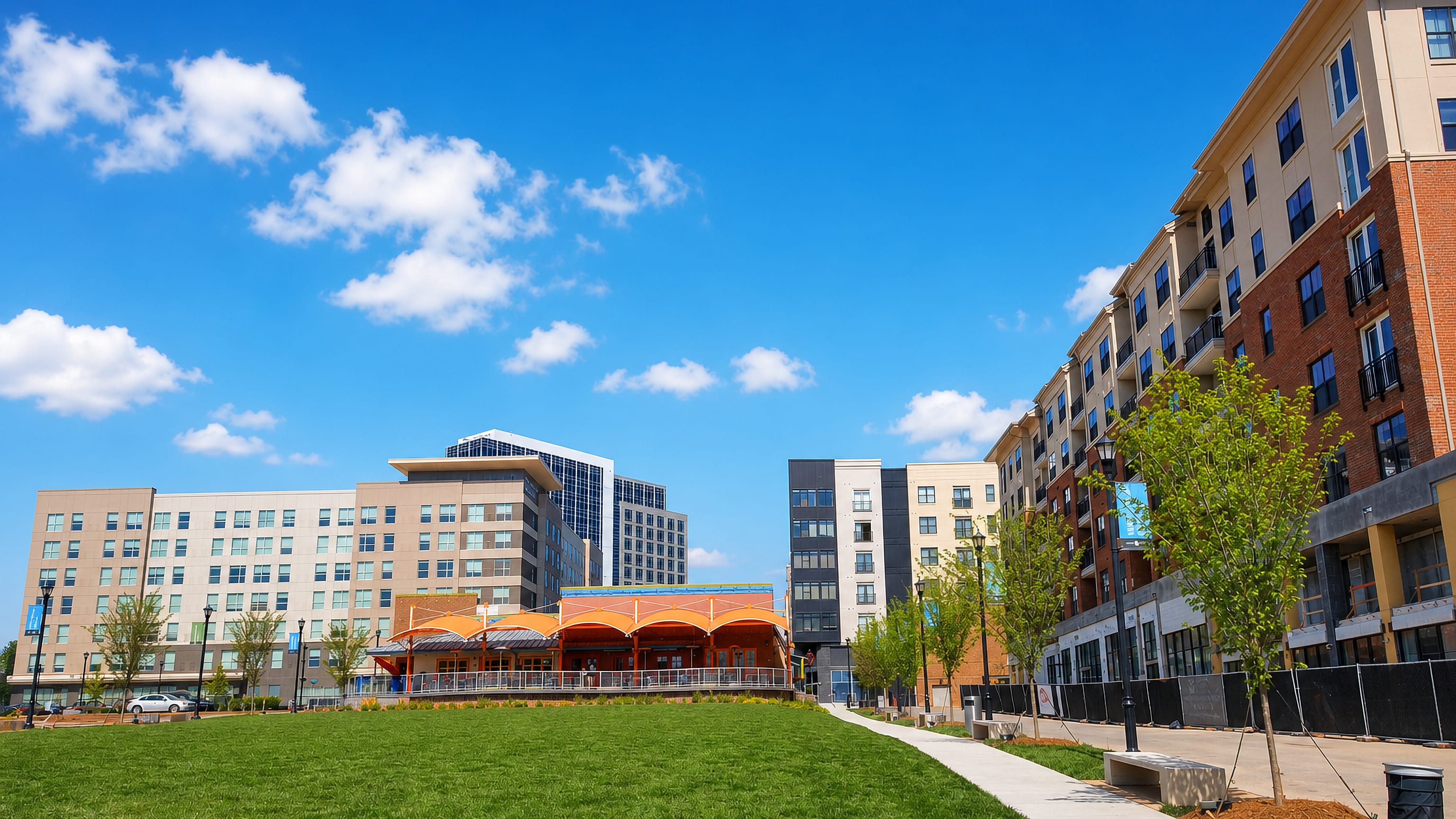 Open park lawn framed by mid-rise mixed-use apartment blocks in the North Hills district of Raleigh.