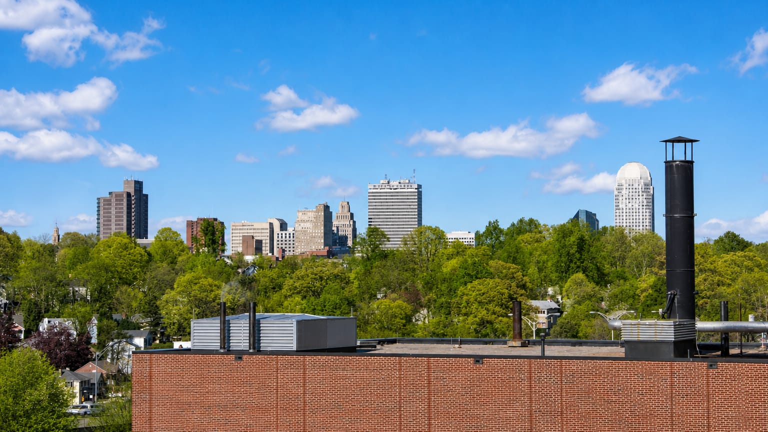 Downtown Winston-Salem, North Carolina skyline rising above green treetops on a clear spring day.