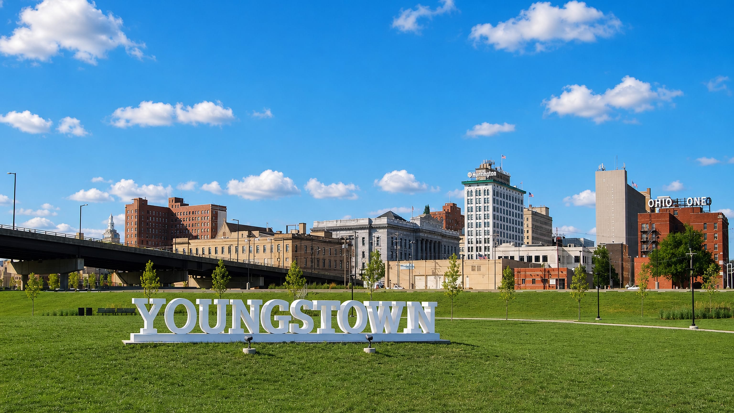 Giant YOUNGSTOWN letters on a parkland lawn before the downtown skyline of Youngstown, Ohio.