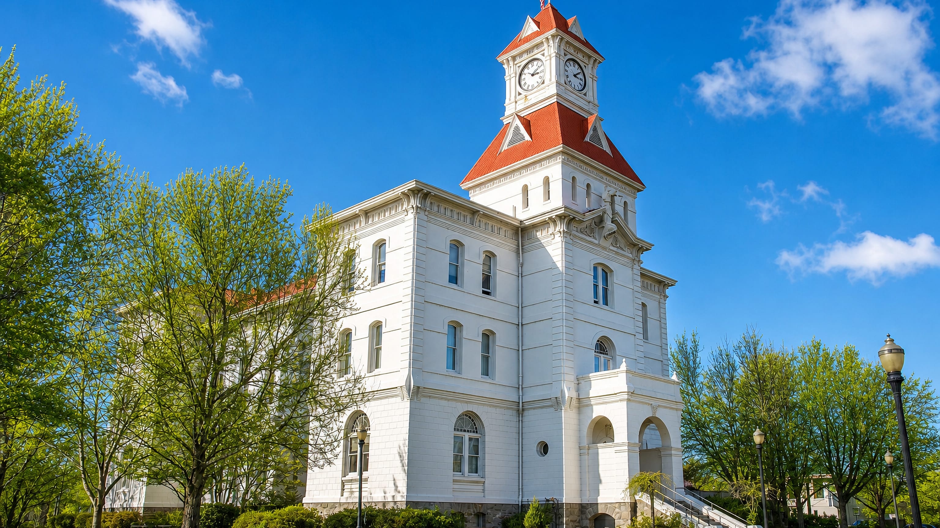 Benton County Courthouse with its red clock tower above lawns and spring trees in Corvallis, Oregon.