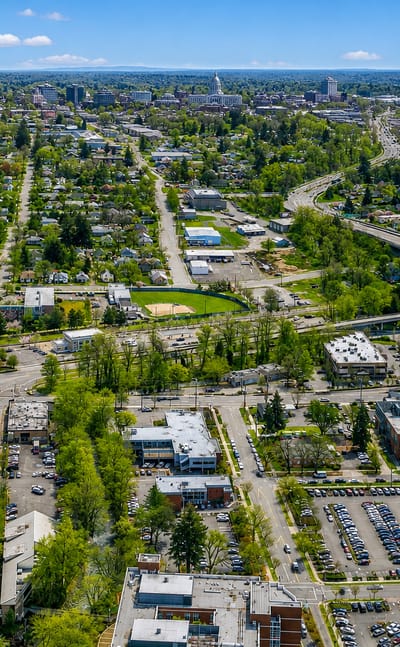 Aerial view of Salem, Oregon with leafy neighborhoods, a curving freeway and the State Capitol in the distance.