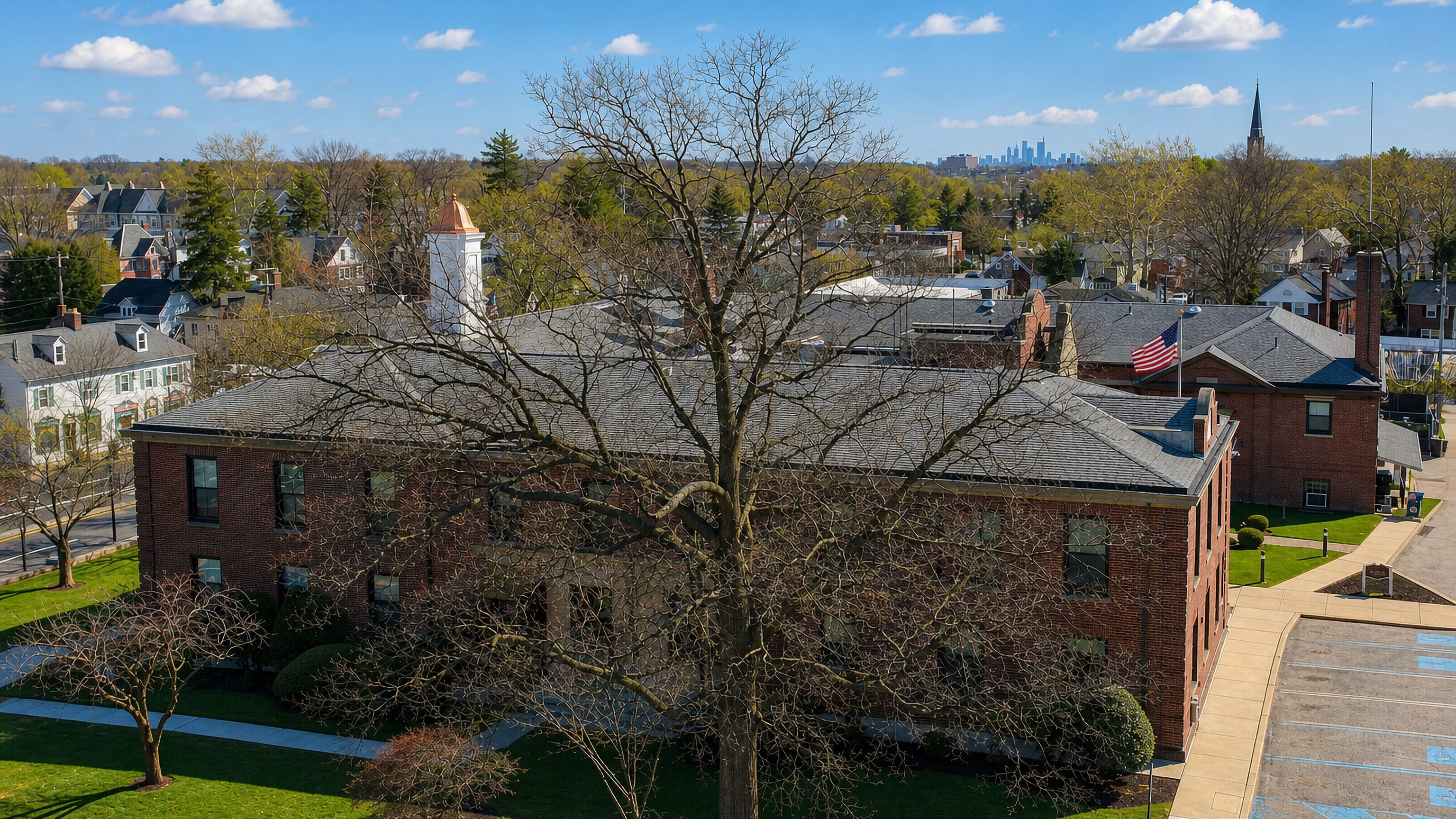 A brick civic building in Abington, Pennsylvania, with a church spire and the Philadelphia skyline beyond.