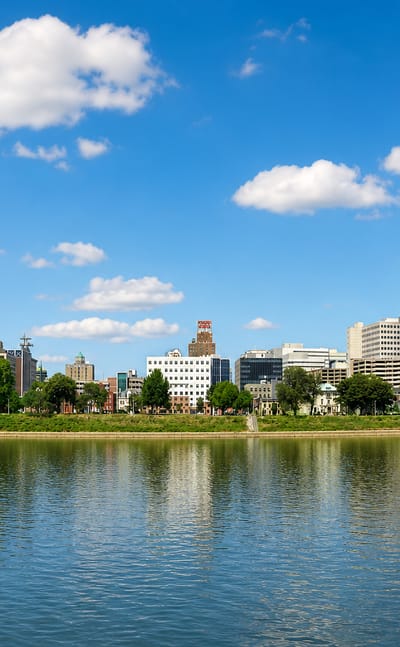 Harrisburg, Pennsylvania skyline with the green Capitol dome and a river bridge across the Susquehanna.