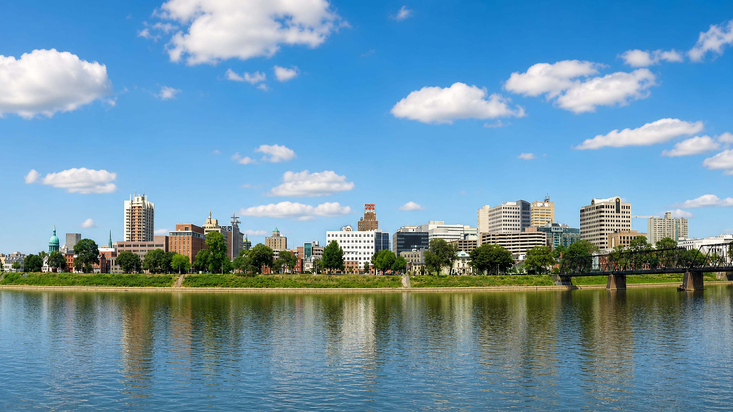 Harrisburg, Pennsylvania skyline with the green Capitol dome and a river bridge across the Susquehanna.