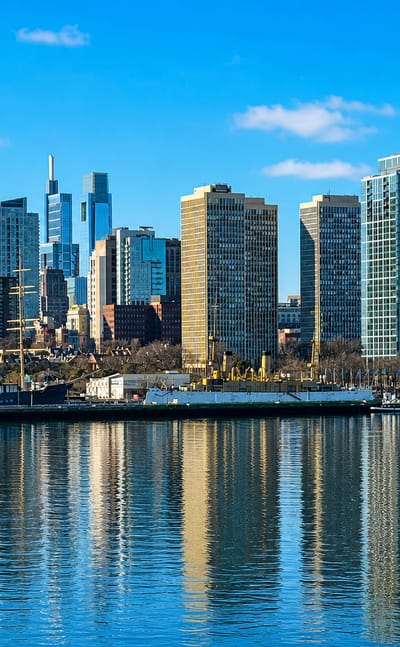 Philadelphia skyline with Center City high-rises reflected across the river on a clear day