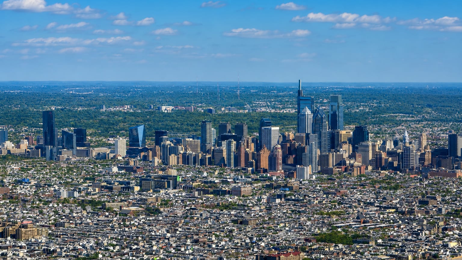 Aerial view of the Philadelphia skyline rising above the dense rowhouse grid seen from Southwest Center City.