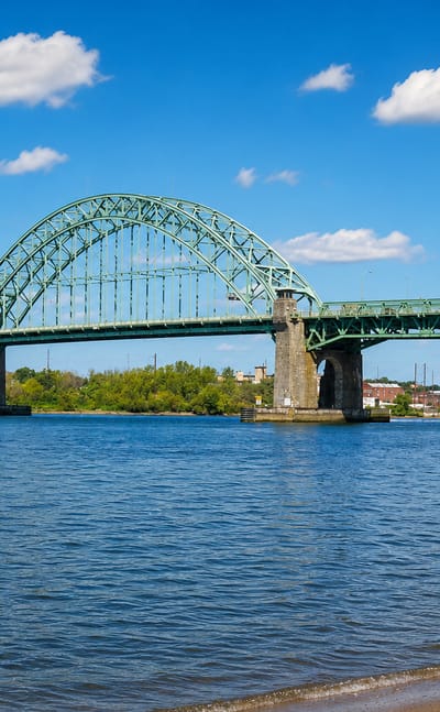 The green steel arch of the Tacony-Palmyra Bridge spanning the Delaware River at Tacony, Philadelphia.