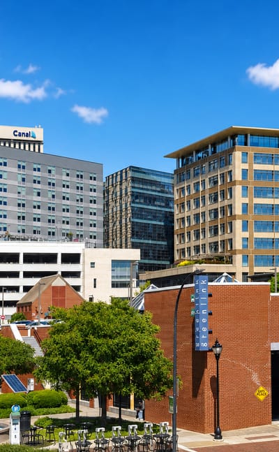 Downtown Greenville, South Carolina, with the Canal building, mid-rise offices and a tree-lined street on a sunny day.