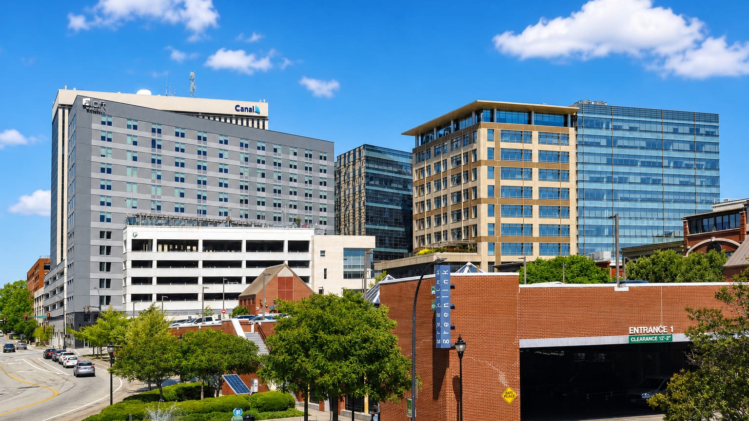 Downtown Greenville, South Carolina, with the Canal building, mid-rise offices and a tree-lined street on a sunny day.