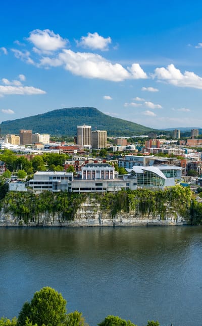 Chattanooga, Tennessee, skyline along the Tennessee River with the blue Walnut Street Bridge and Lookout Mountain beyond.
