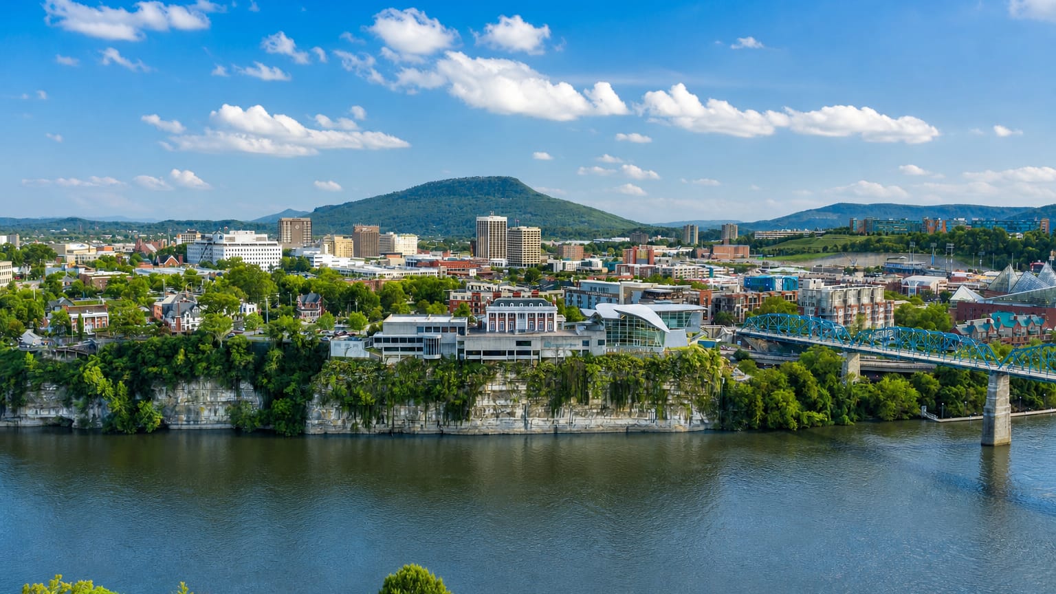 Chattanooga, Tennessee, skyline along the Tennessee River with the blue Walnut Street Bridge and Lookout Mountain beyond.