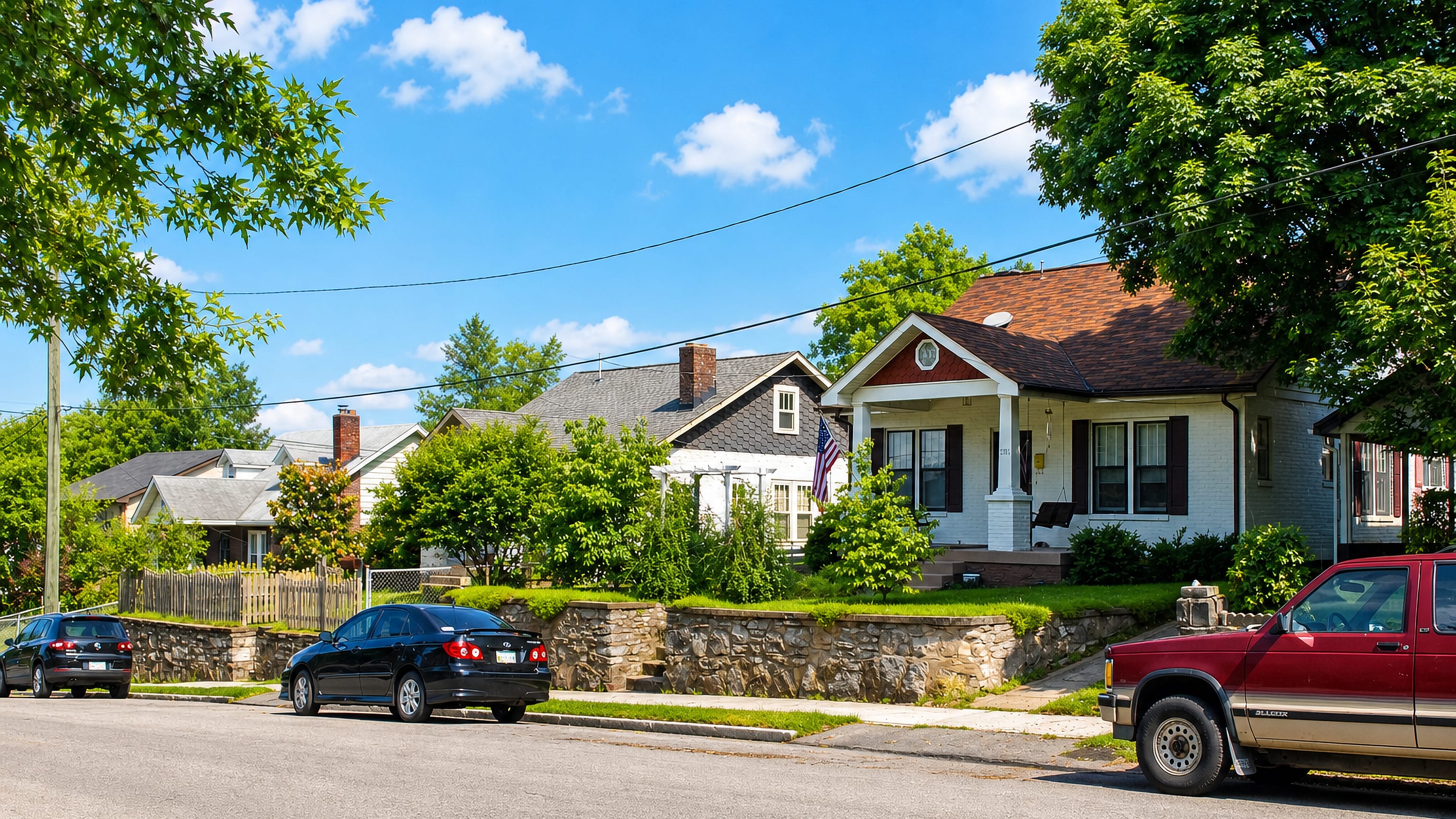 Craftsman bungalows behind a stone retaining wall on a tree-lined street in East Nashville.