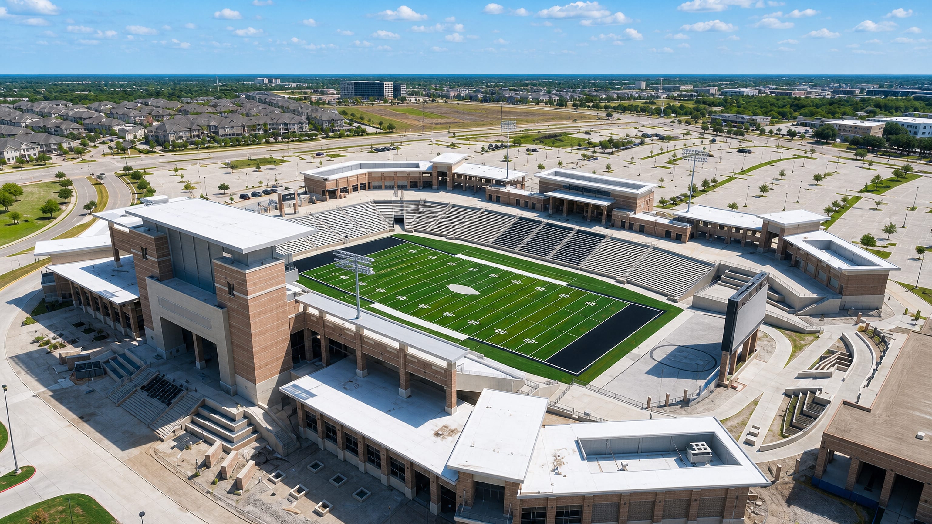 Aerial view of a large football stadium and its parking lots amid the suburbs of Allen, Texas.
