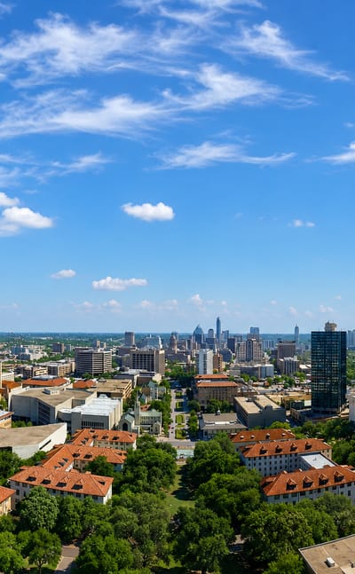 Aerial view of the University of Texas campus with red-tiled roofs and the downtown Austin skyline beyond
