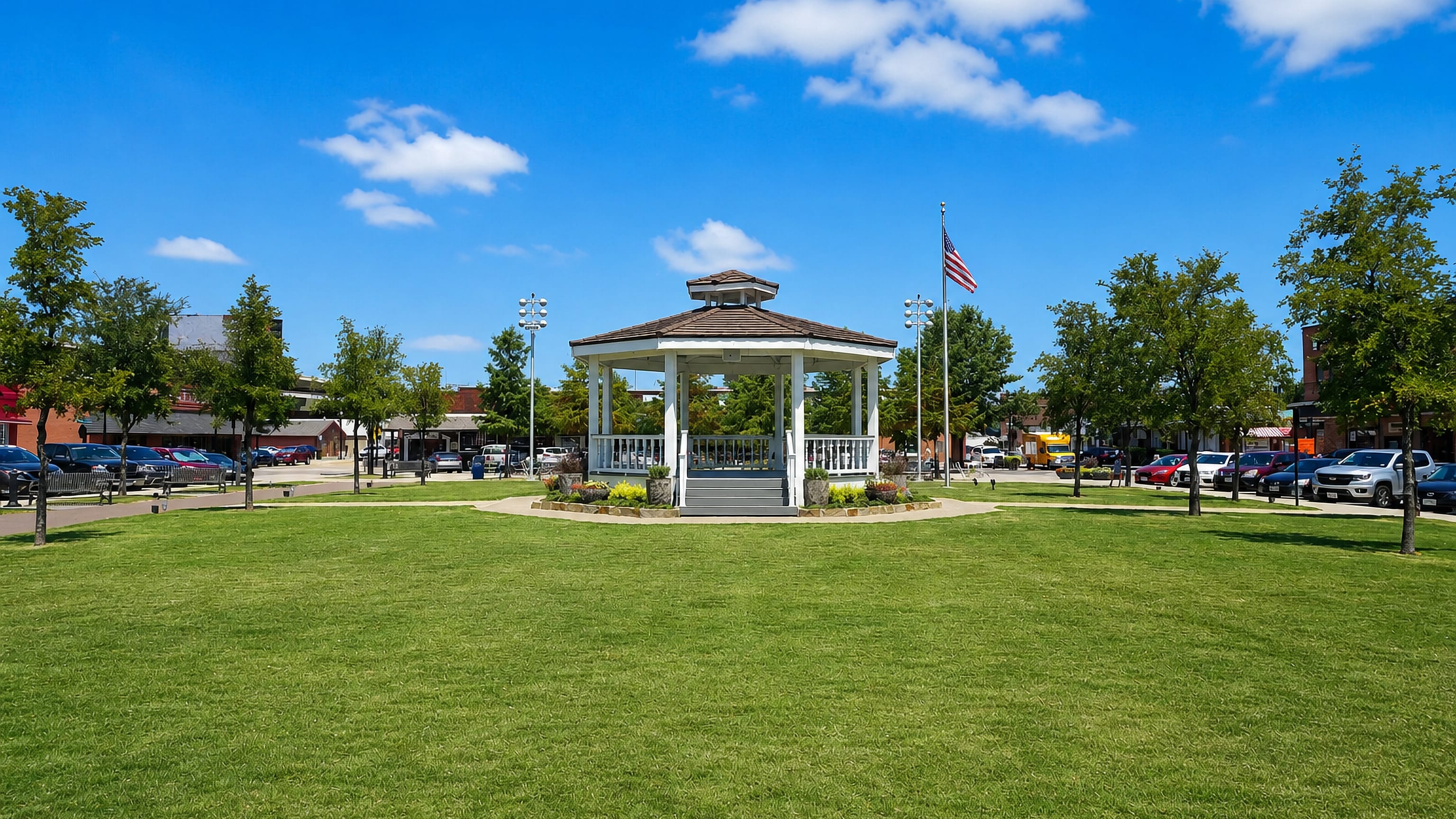 Gazebo and flagpole on the green at Carrollton, Texas, with the historic downtown square storefronts behind.