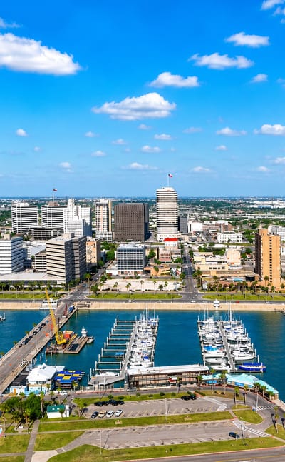 Aerial view of downtown Corpus Christi, Texas, with its bayfront marina full of sailboats and waterfront towers.