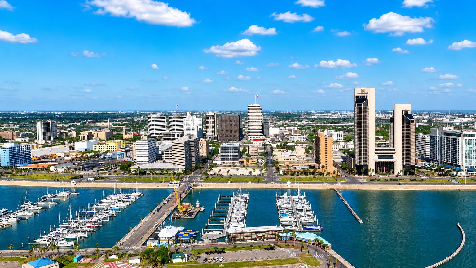 Aerial view of downtown Corpus Christi, Texas, with its bayfront marina full of sailboats and waterfront towers.
