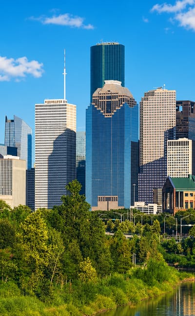 Houston downtown towers above Buffalo Bayou greenery on a sunny day
