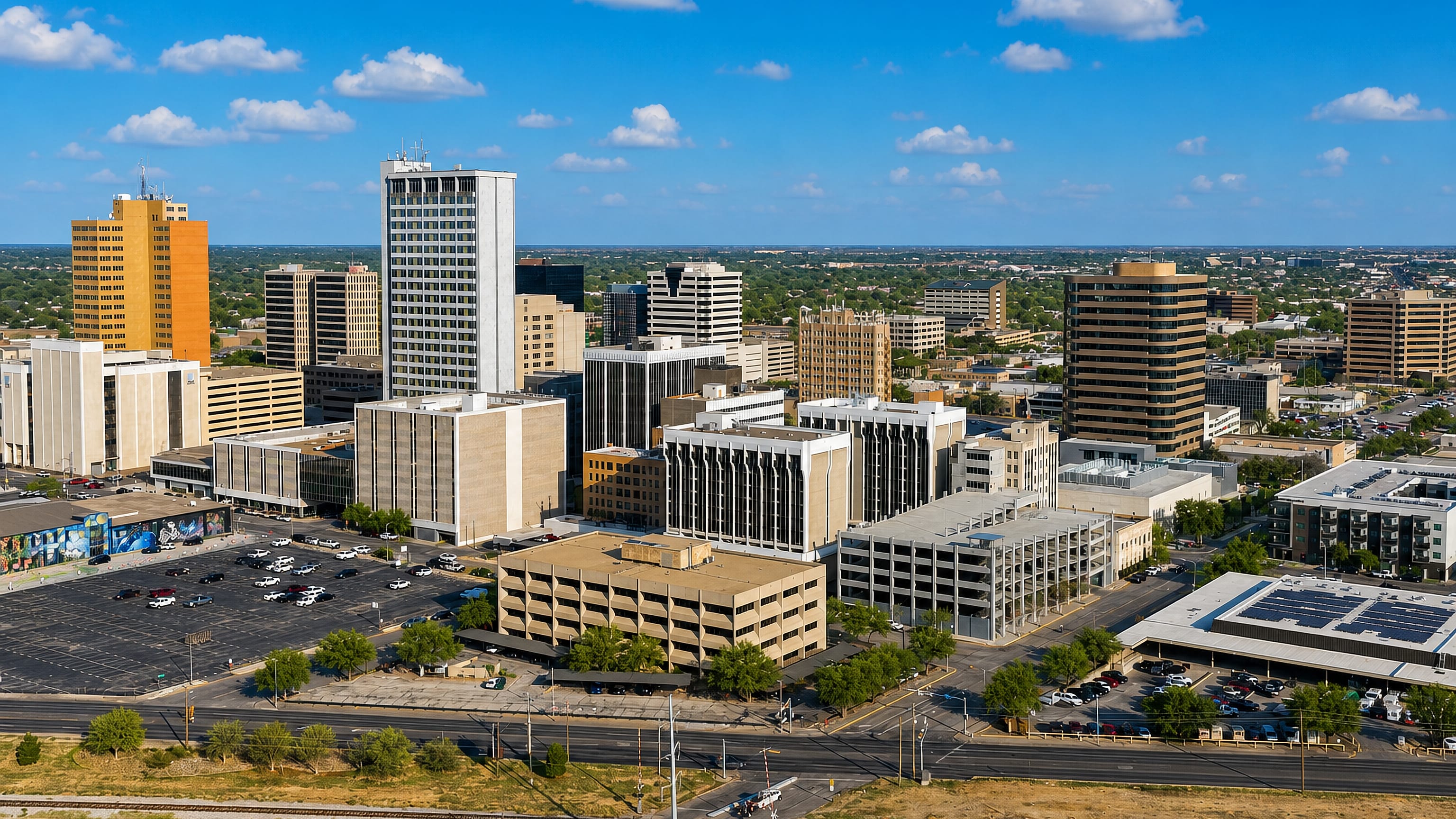 Midland's downtown office towers rising above parking lots and rail tracks on the flat West Texas plain.