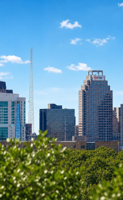 San Antonio skyline with the green-domed Tower Life Building and PNC tower rising above a leafy tree canopy