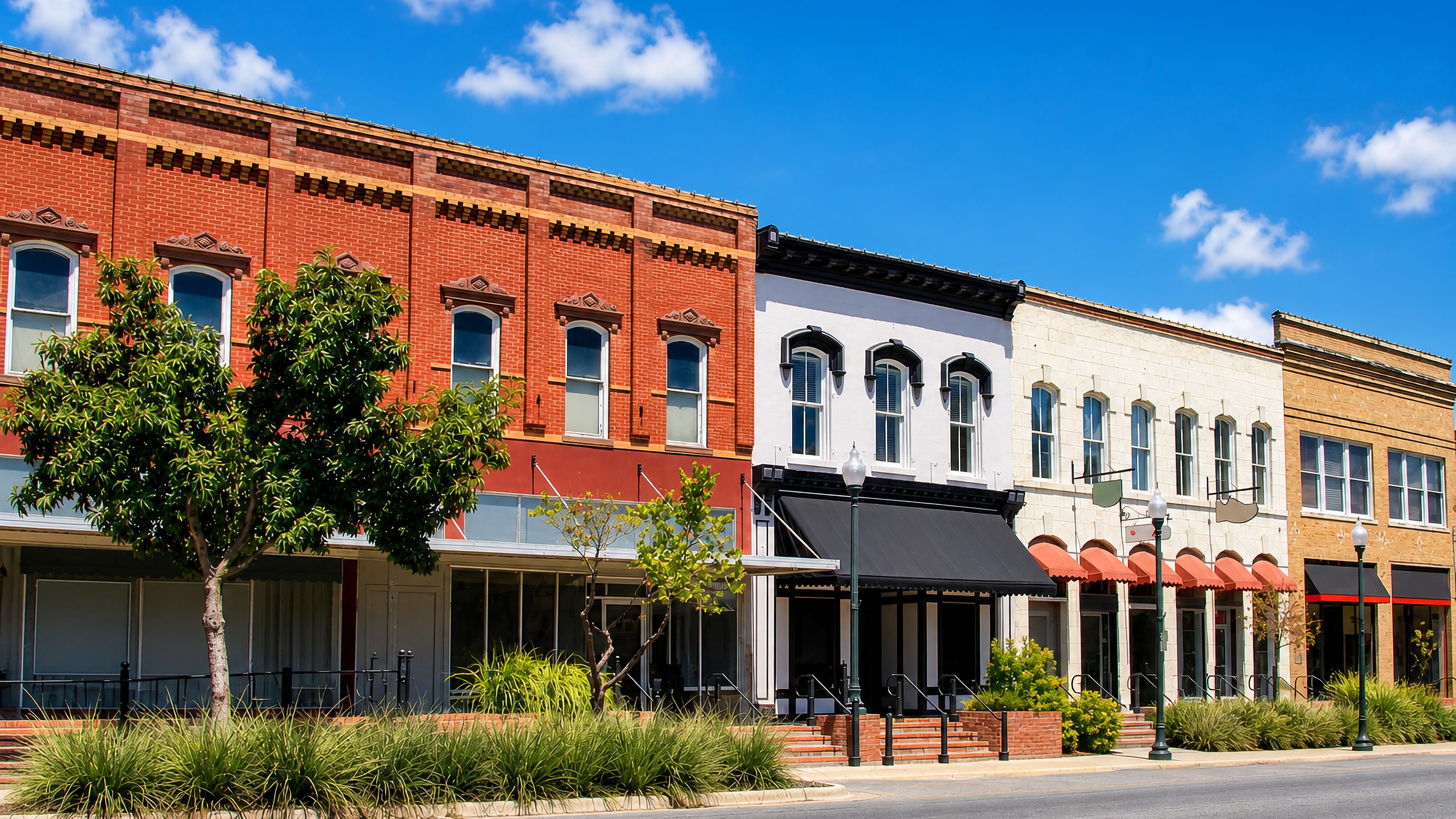 Historic brick and stucco storefronts under awnings along a downtown street in San Marcos, Texas.