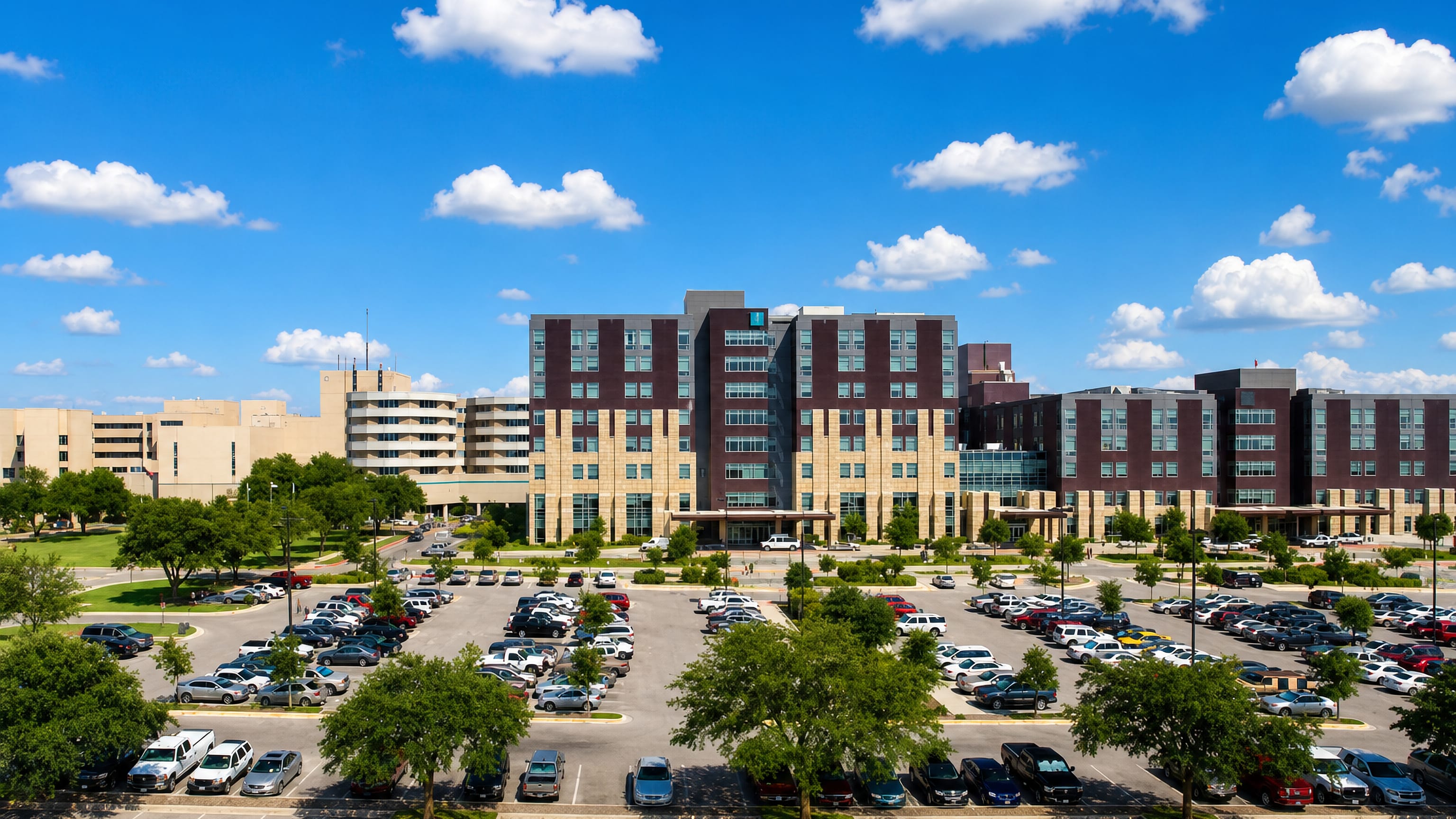 Multi-storey medical campus buildings above a tree-lined parking lot in Temple, Texas.
