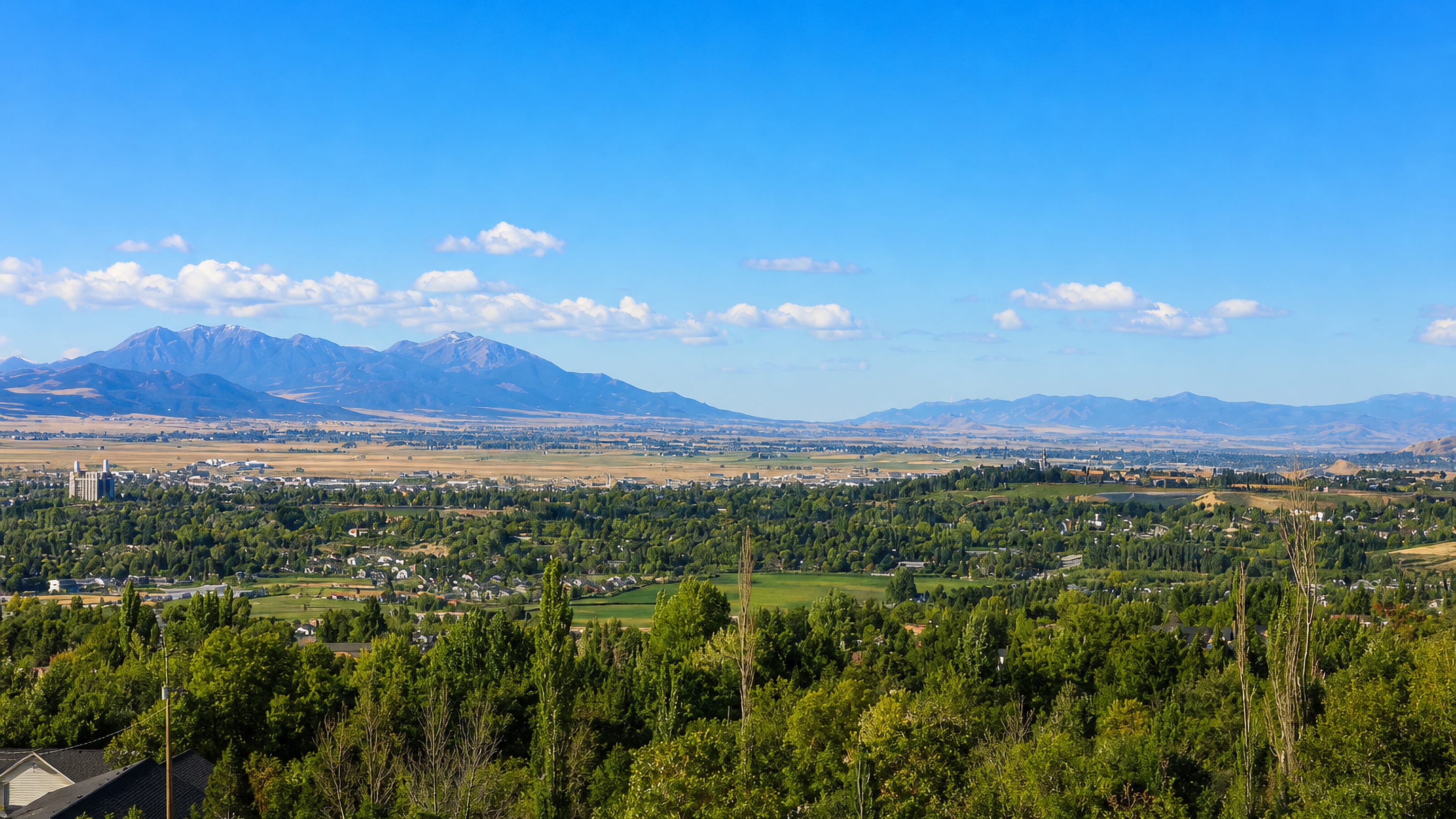 Wooded foreground and Cache Valley farmland stretching to mountains beyond Logan, Utah.