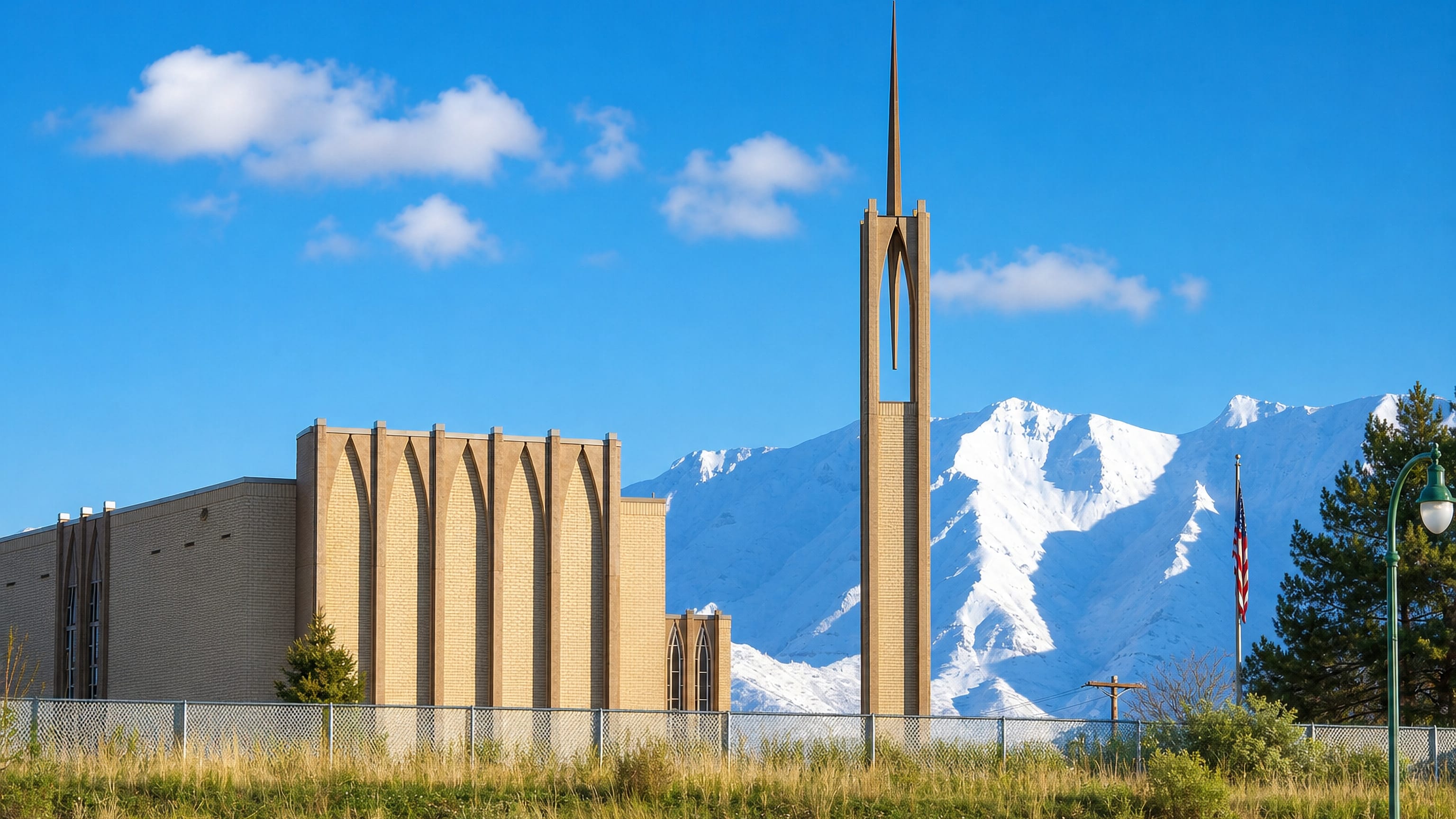 A brick chapel with a slender spire below the snow-capped Wasatch Range in Orem, Utah.