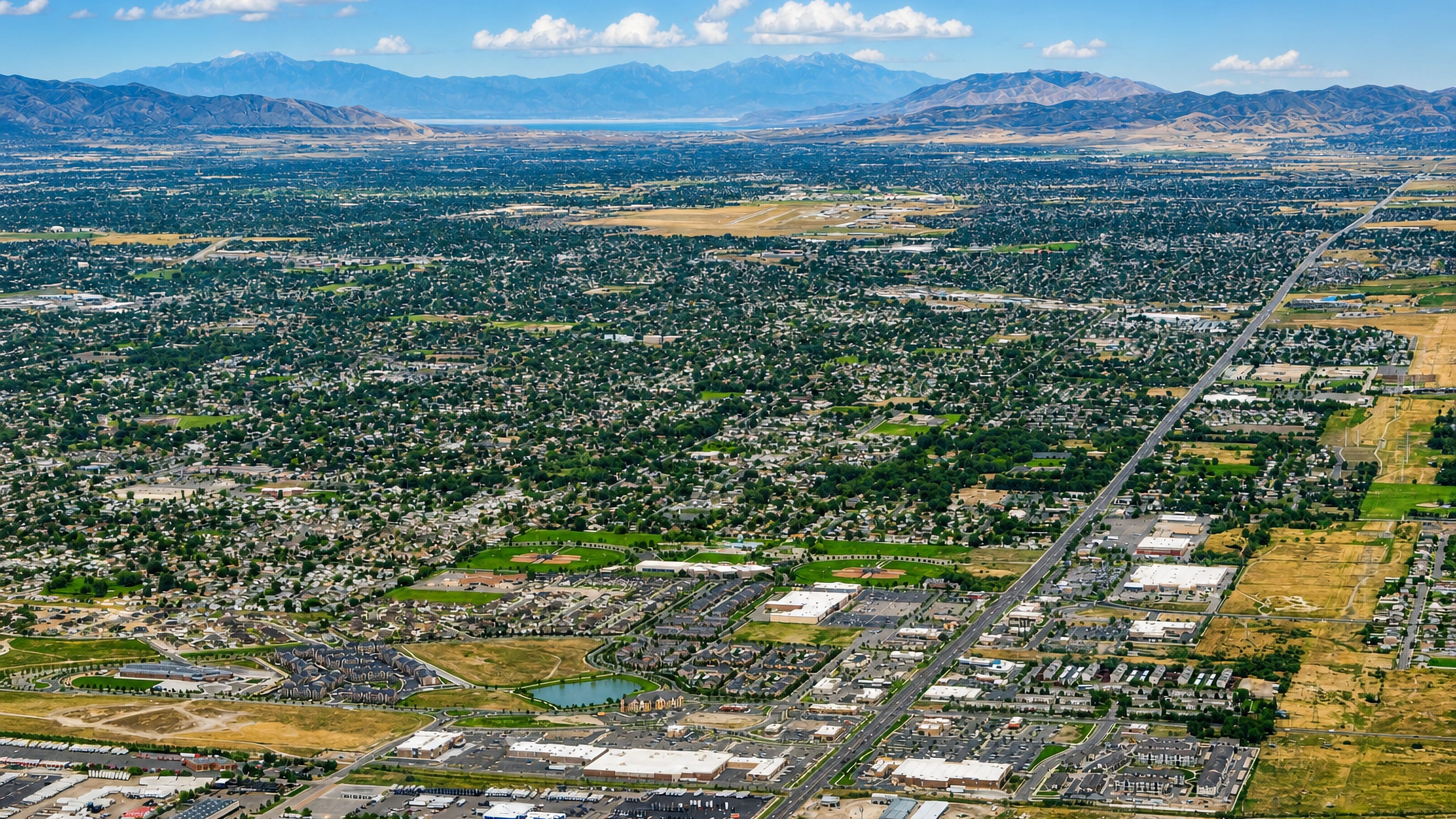 Aerial view across West Valley City's suburban grid in the Salt Lake Valley, with the Wasatch mountains beyond