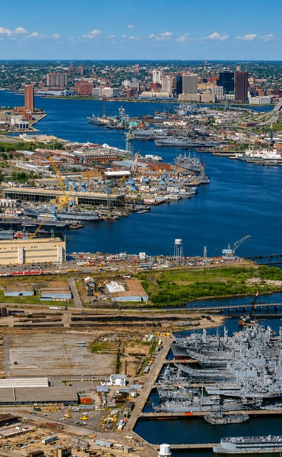 Aerial view of Norfolk, Virginia, with its naval shipyard, warships and downtown skyline across the harbor.