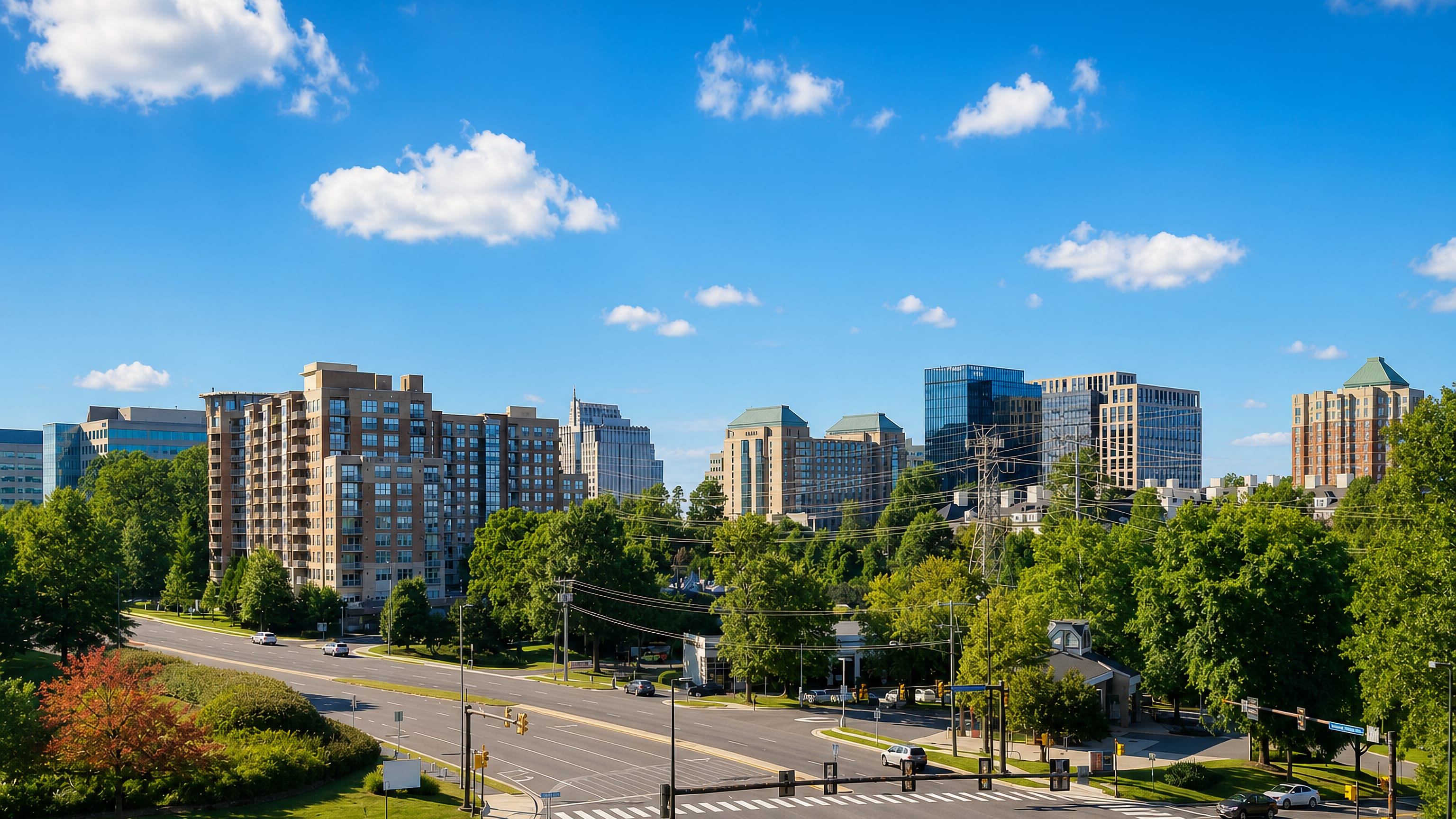 Mid-rise office and apartment towers rising above wooded streets at a boulevard crossing in Reston, Virginia.