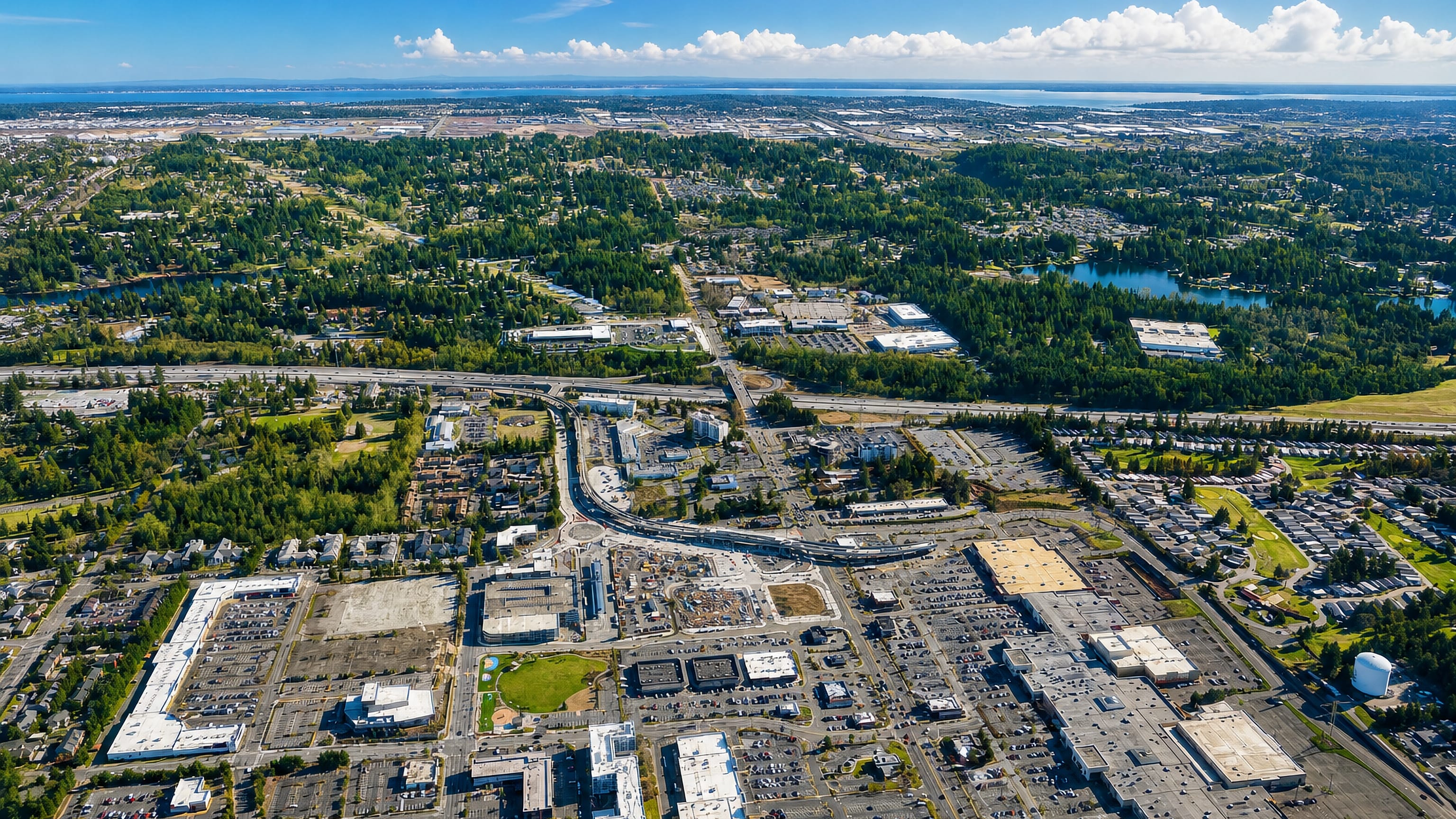 Aerial view of Federal Way, Washington, with shopping centres, forested neighbourhoods and Puget Sound beyond.