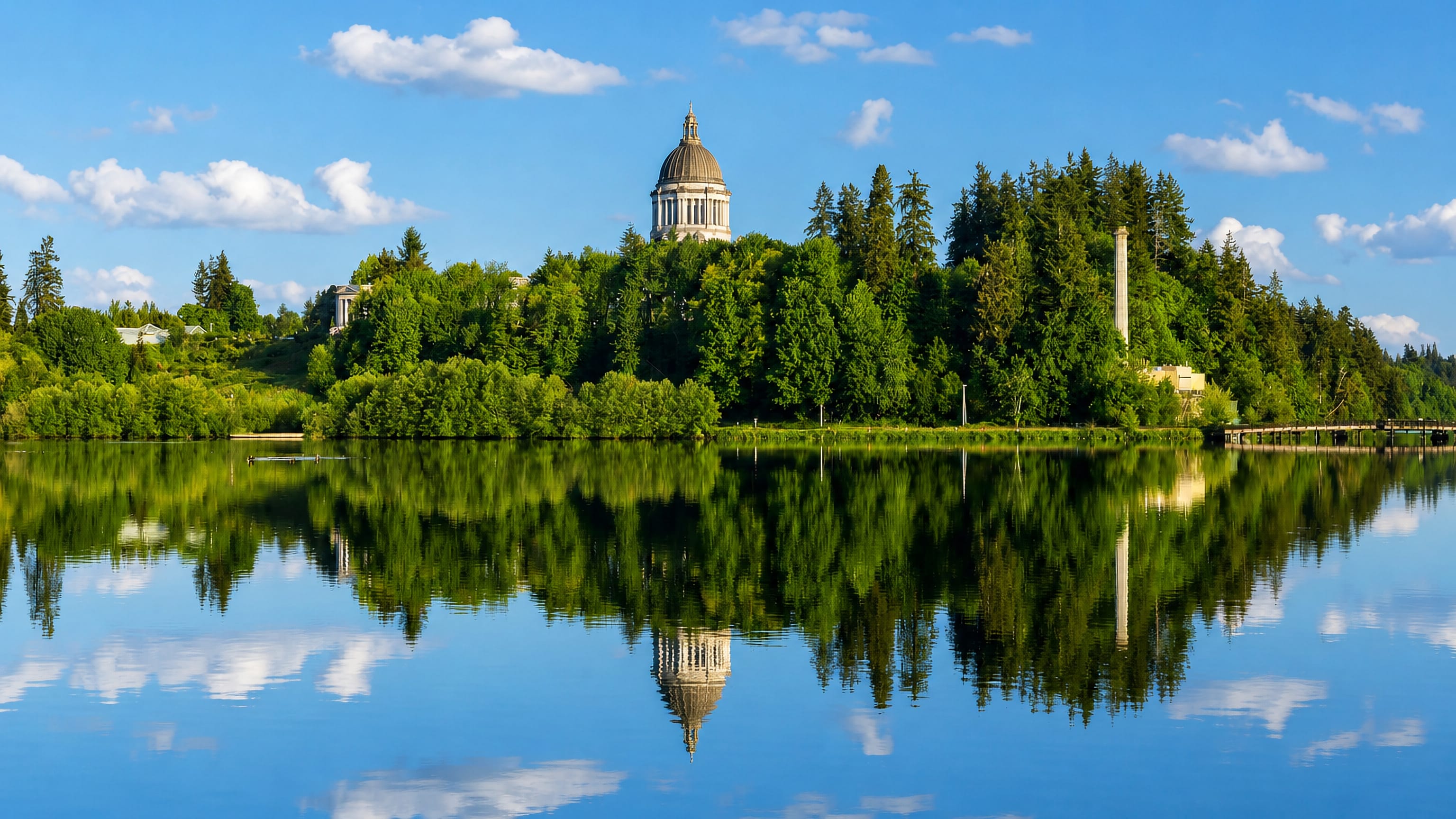Washington State Capitol dome rising above the forested bluff and Capitol Lake in Olympia, Washington.