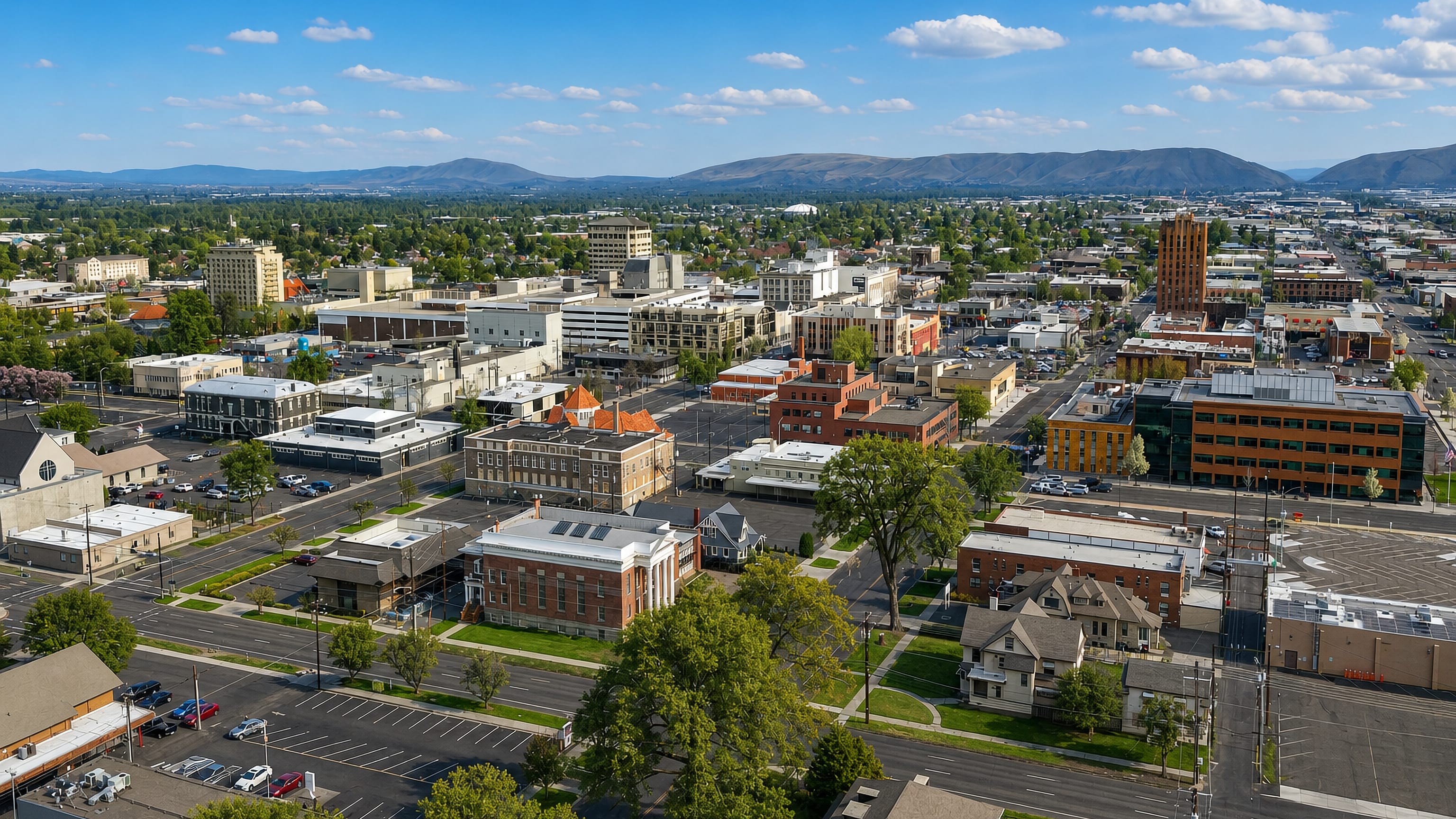 Downtown Yakima, Washington from above, brick low-rise blocks and a tall brick tower below dry valley ridges.