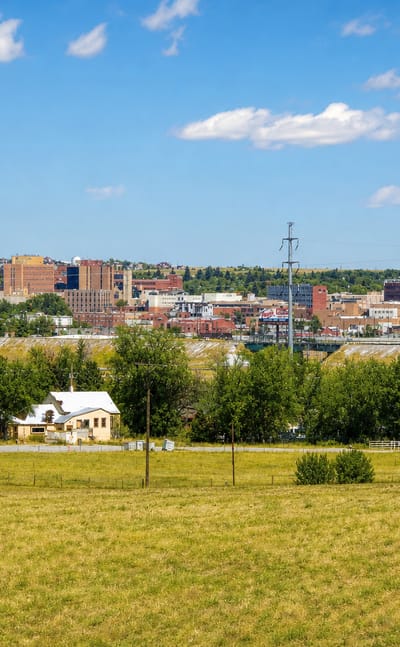 Downtown Cheyenne, Wyoming seen across an open grassy field under a blue summer sky.