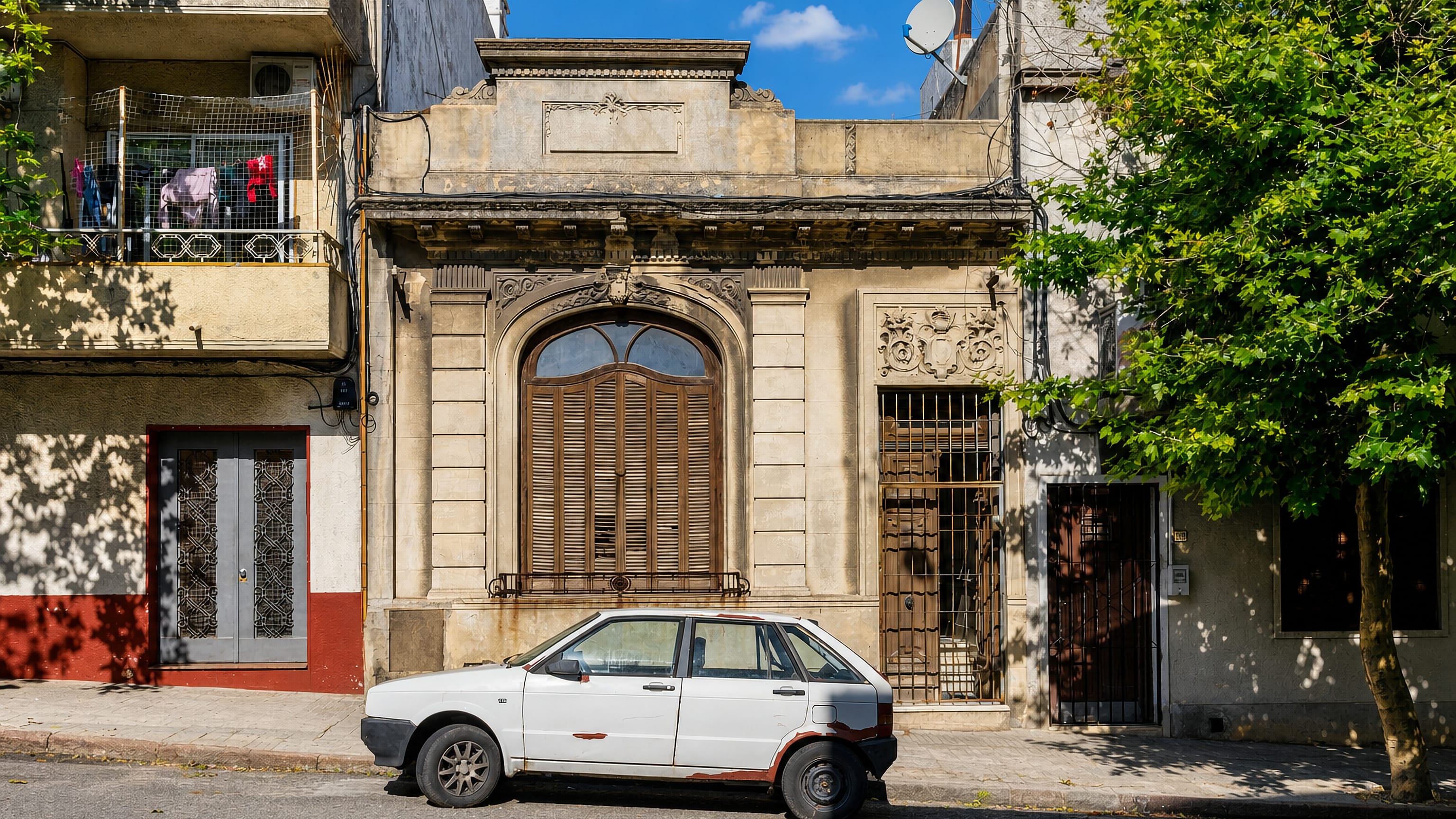 Weathered period facade and an old parked hatchback on a street in Barrio Sur, Montevideo.
